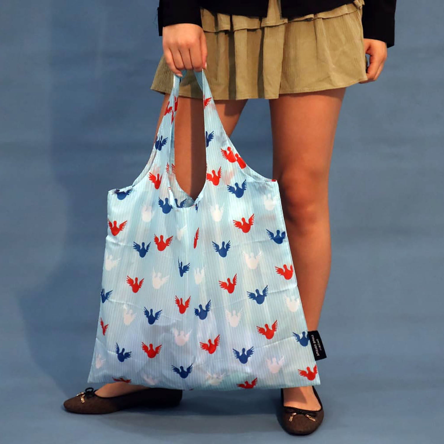 Close-up of the Angels print on a sky-blue polyester tote bag