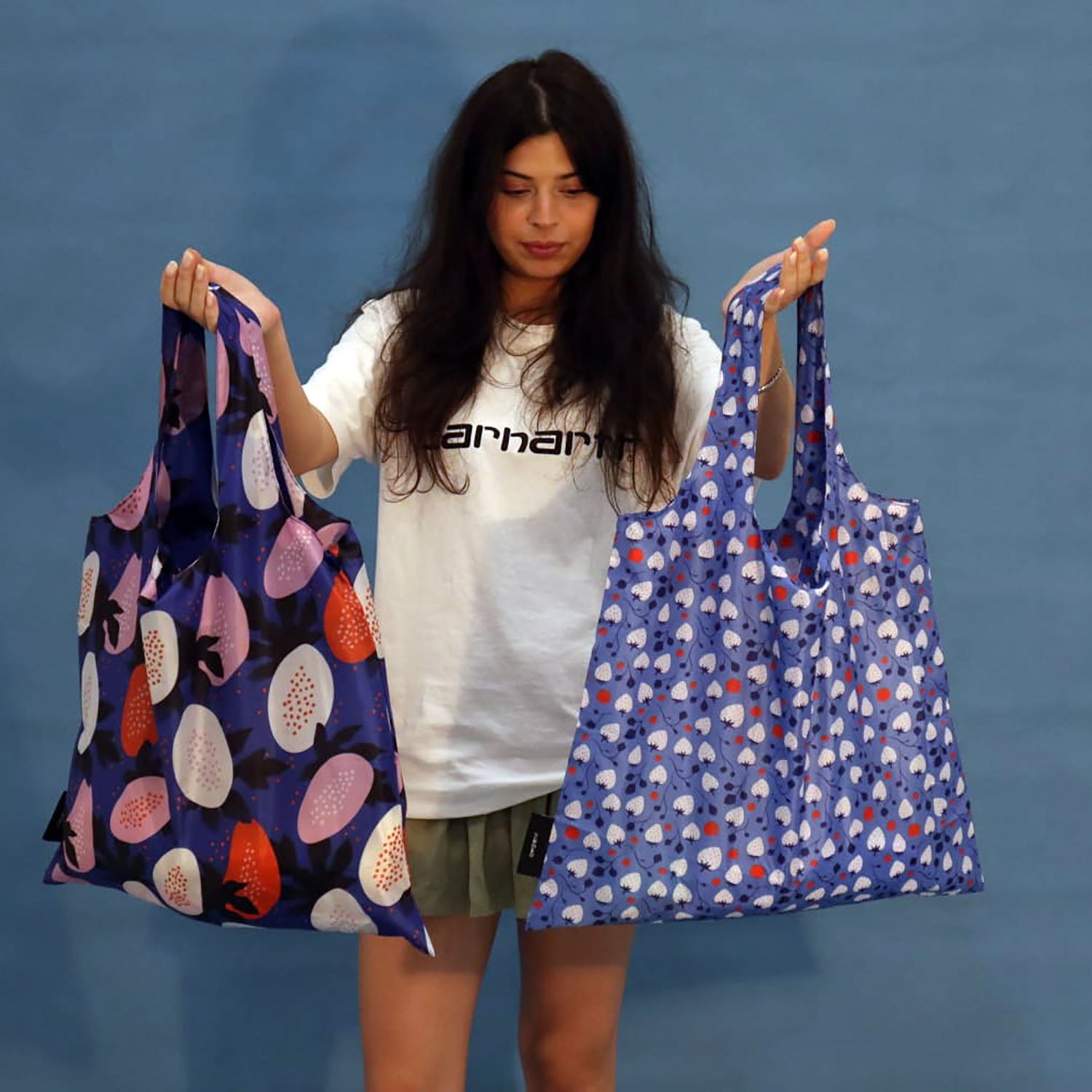 Person wearing a blue Strawberries tote bag over the shoulder