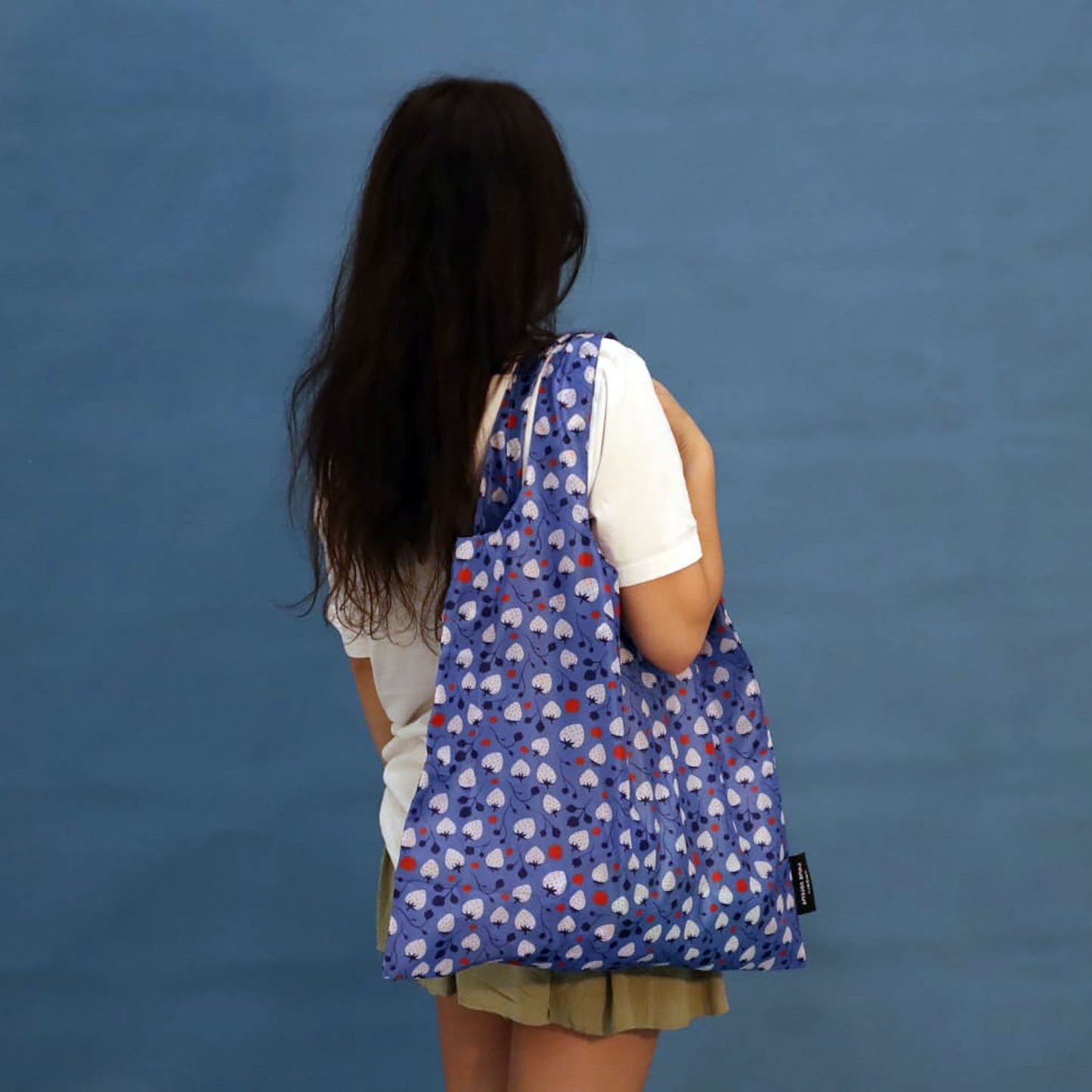 Person carrying a blue Strawberries tote bag