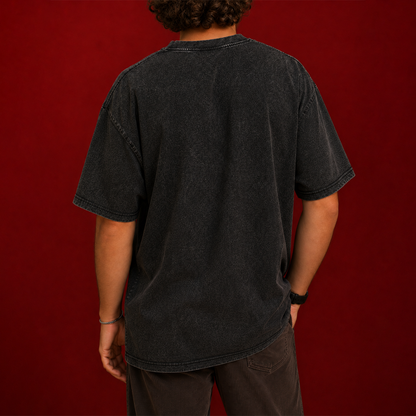 A person shown from the back wearing an oversized faded black t-shirt and dark brown pants, standing against a solid dark red background.