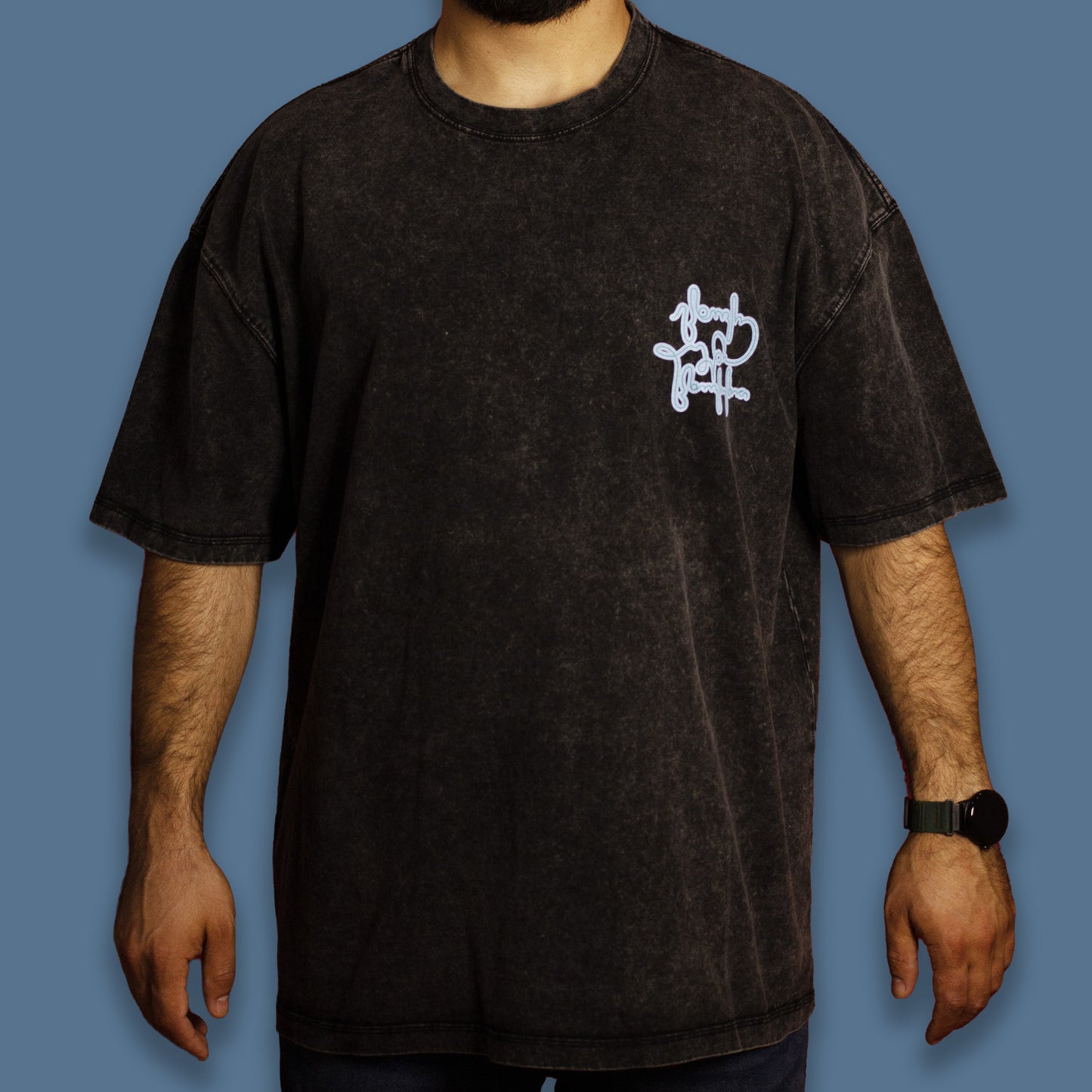 Person wearing a black acid-washed T-shirt with a sky-blue graphic