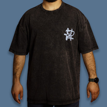 Person wearing a black acid-washed T-shirt with a sky-blue graphic
