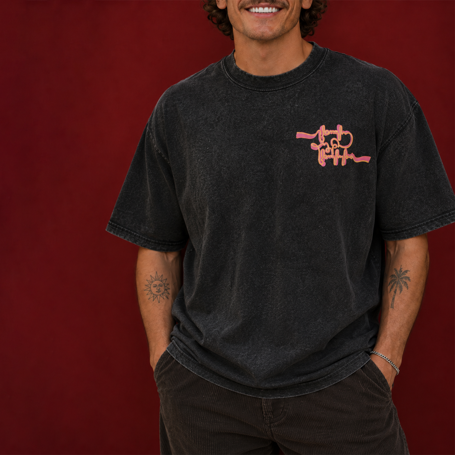 Person wearing a black acid-washed T-shirt with an orange chest graphic