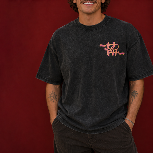 Person wearing a black acid-washed T-shirt with an orange chest graphic
