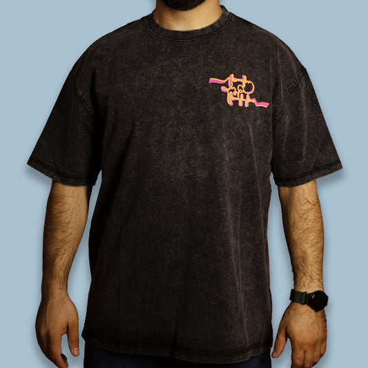 Person wearing a black acid-washed T-shirt with an orange chest graphic