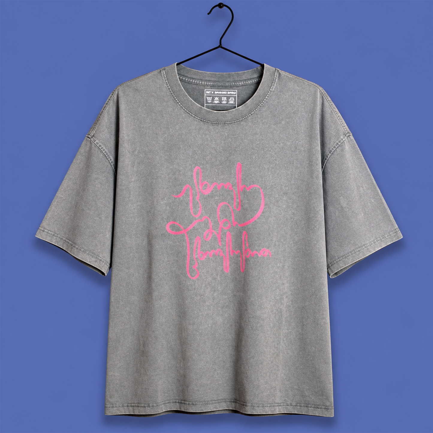 A gray mineral-wash t-shirt with a pink script graphic reading 'brave girl everything' on the front, hanging on a black hanger against a solid blue background.