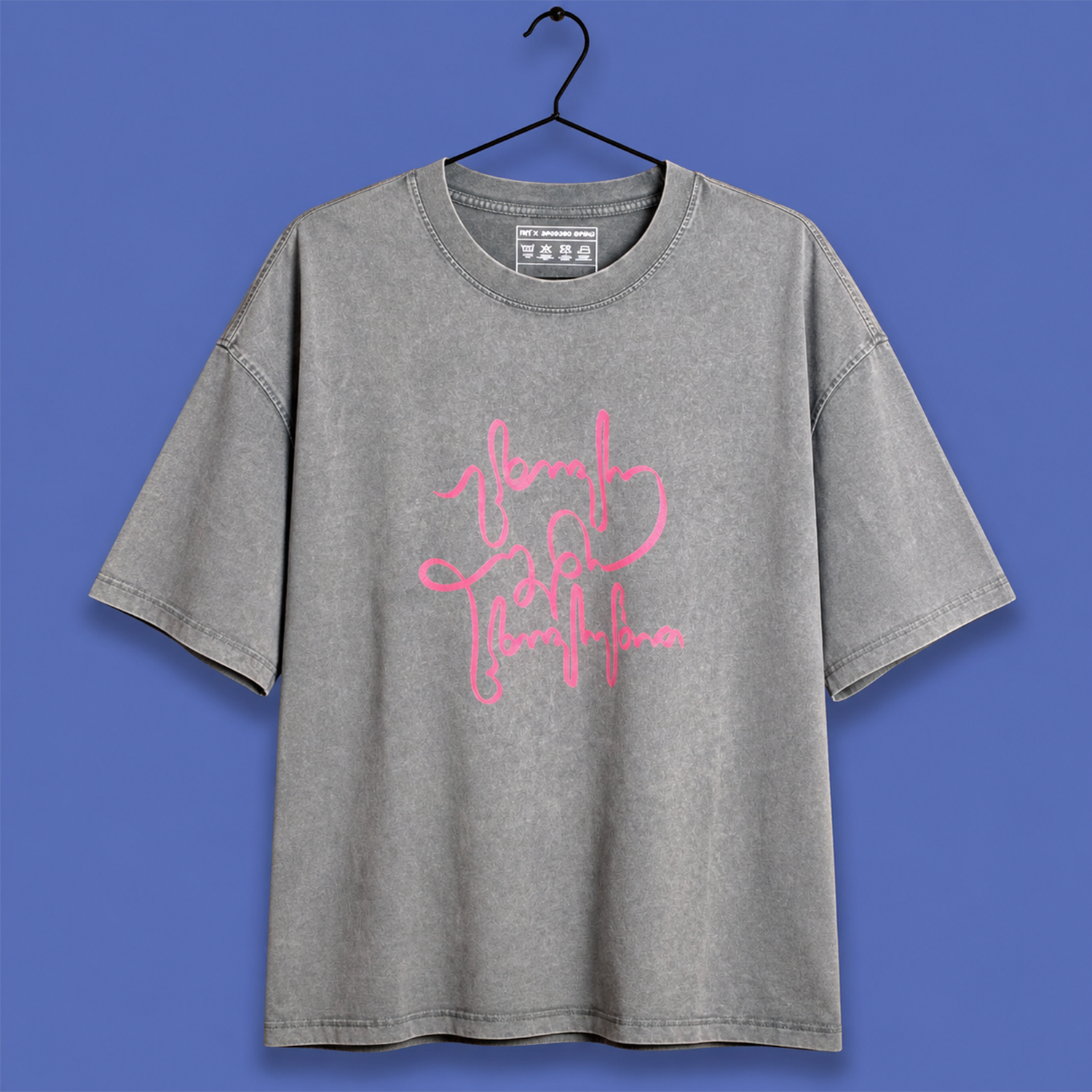 A gray mineral-wash t-shirt with a pink script graphic reading 'brave girl everything' on the front, hanging on a black hanger against a solid blue background.
