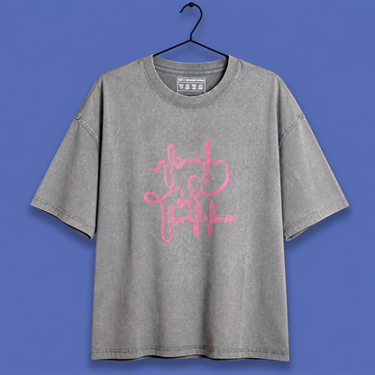 A gray mineral-wash t-shirt with a pink script graphic reading 'brave girl everything' on the front, hanging on a black hanger against a solid blue background.