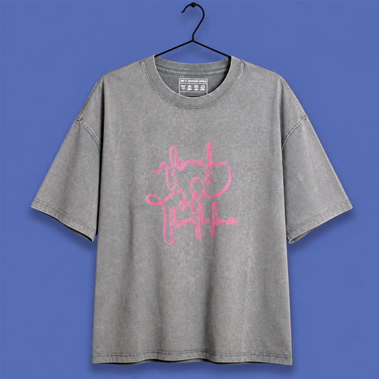 A gray mineral-wash t-shirt with a pink script graphic reading 'brave girl everything' on the front, hanging on a black hanger against a solid blue background.