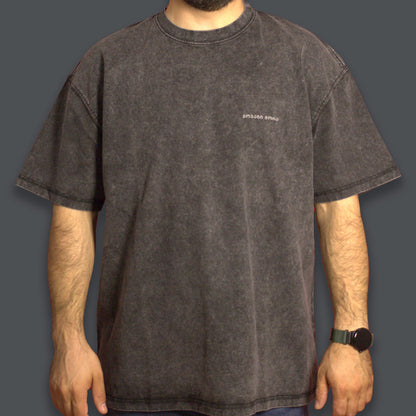 Person wearing a black acid-washed T-shirt with a tonal Georgian logo