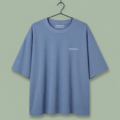 light blue crewneck t-shirt with a small white 'SPEED SHOP' logo on the left chest, set against a solid sage green background.