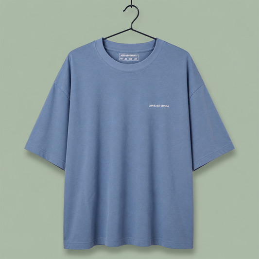 light blue crewneck t-shirt with a small white 'SPEED SHOP' logo on the left chest, set against a solid sage green background.