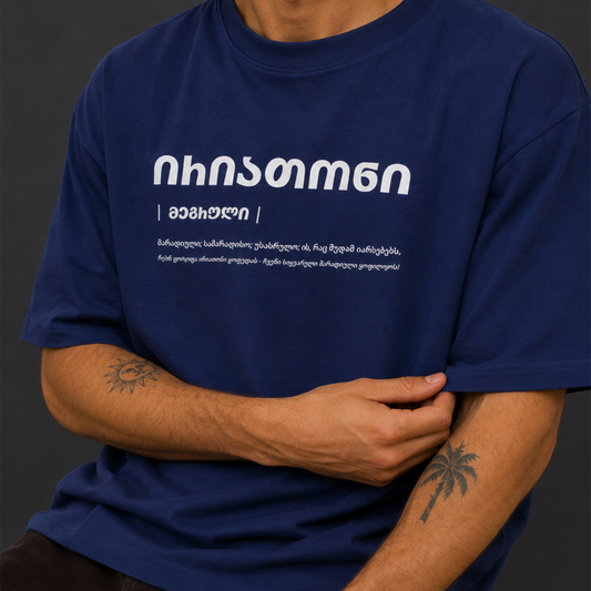 A person wearing a navy blue short-sleeve T-shirt with white Georgian text printed across the chest, shown against a dark gray background.