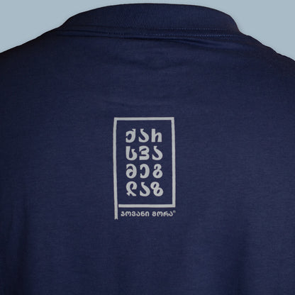 Close-up of a small white typographic graphic on the back of a navy T-shirt