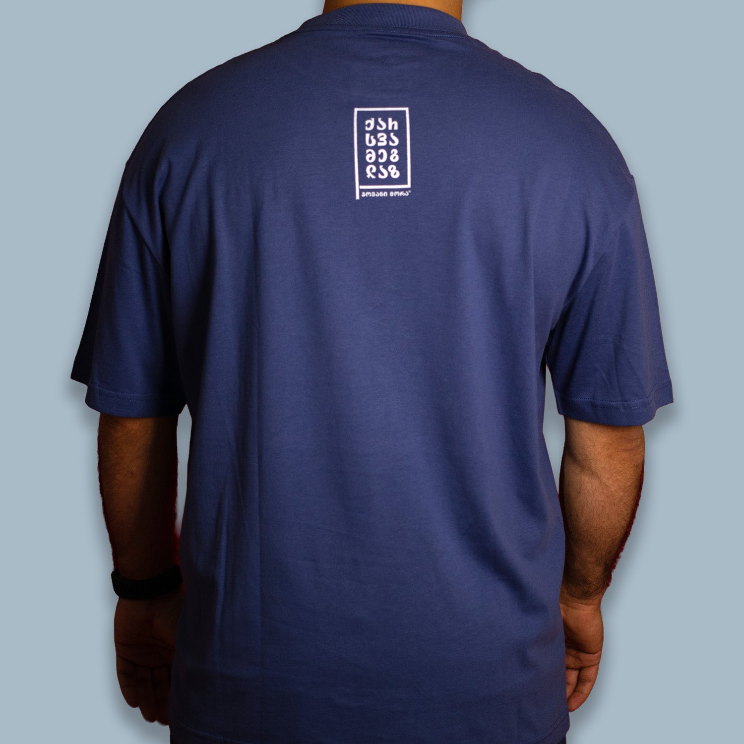 Man wearing a navy blue T-shirt with a small white graphic on the back