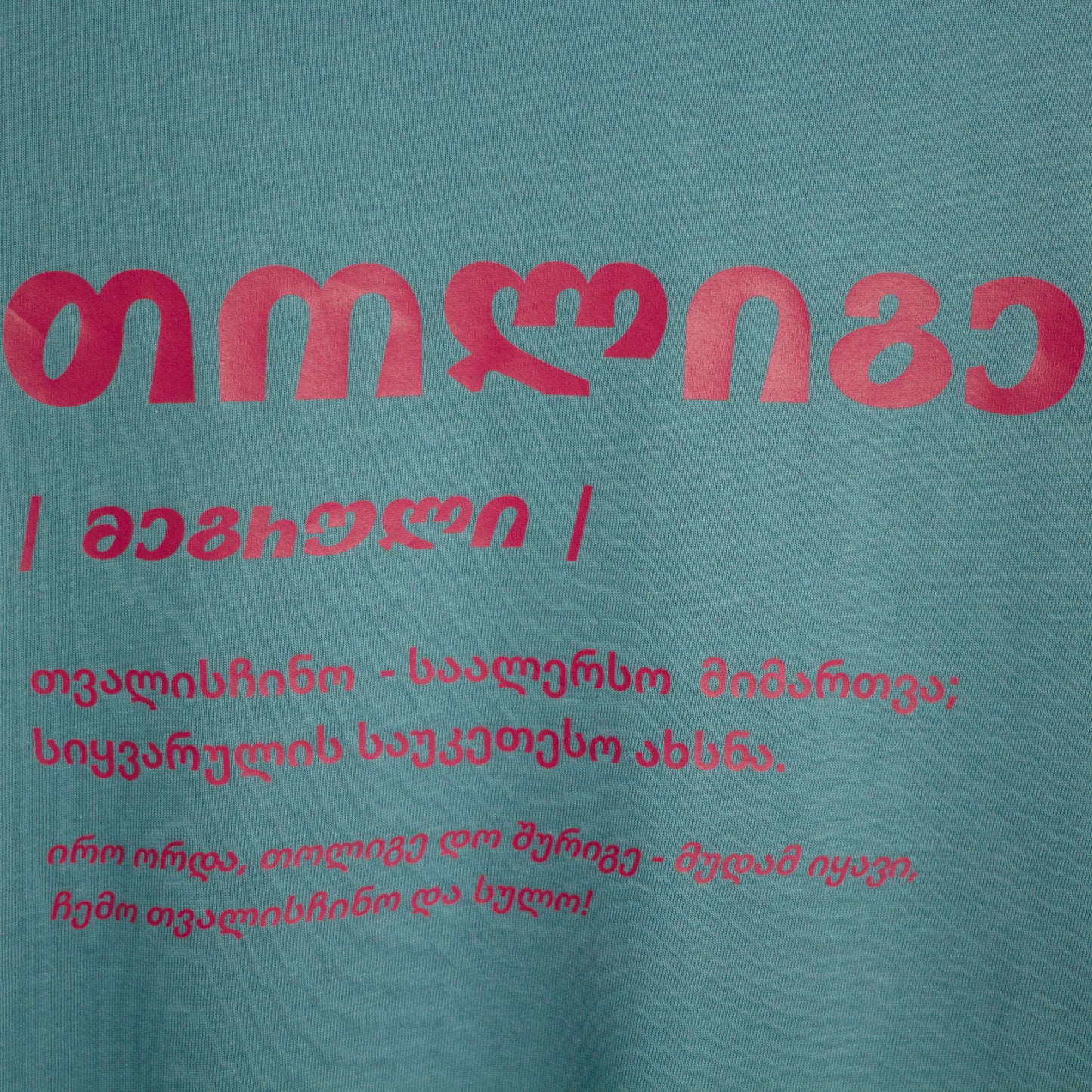 Close-up of red Tholige text printed on pale green fabric