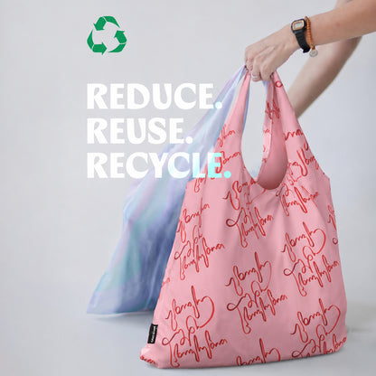Pink reusable bag with text and blue gradient bag, with 'Reduce. Reuse. Recycle.' text and recycling symbol.